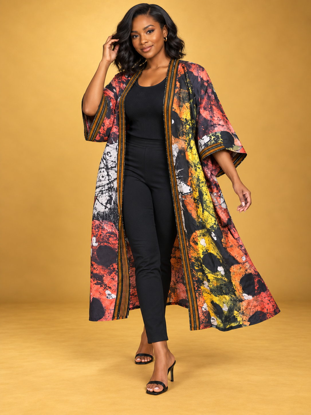 Model wearing the Sunset Batik Long Kimono in orange, black and white African batik print by ILÉ AYỌ̀KÁ.