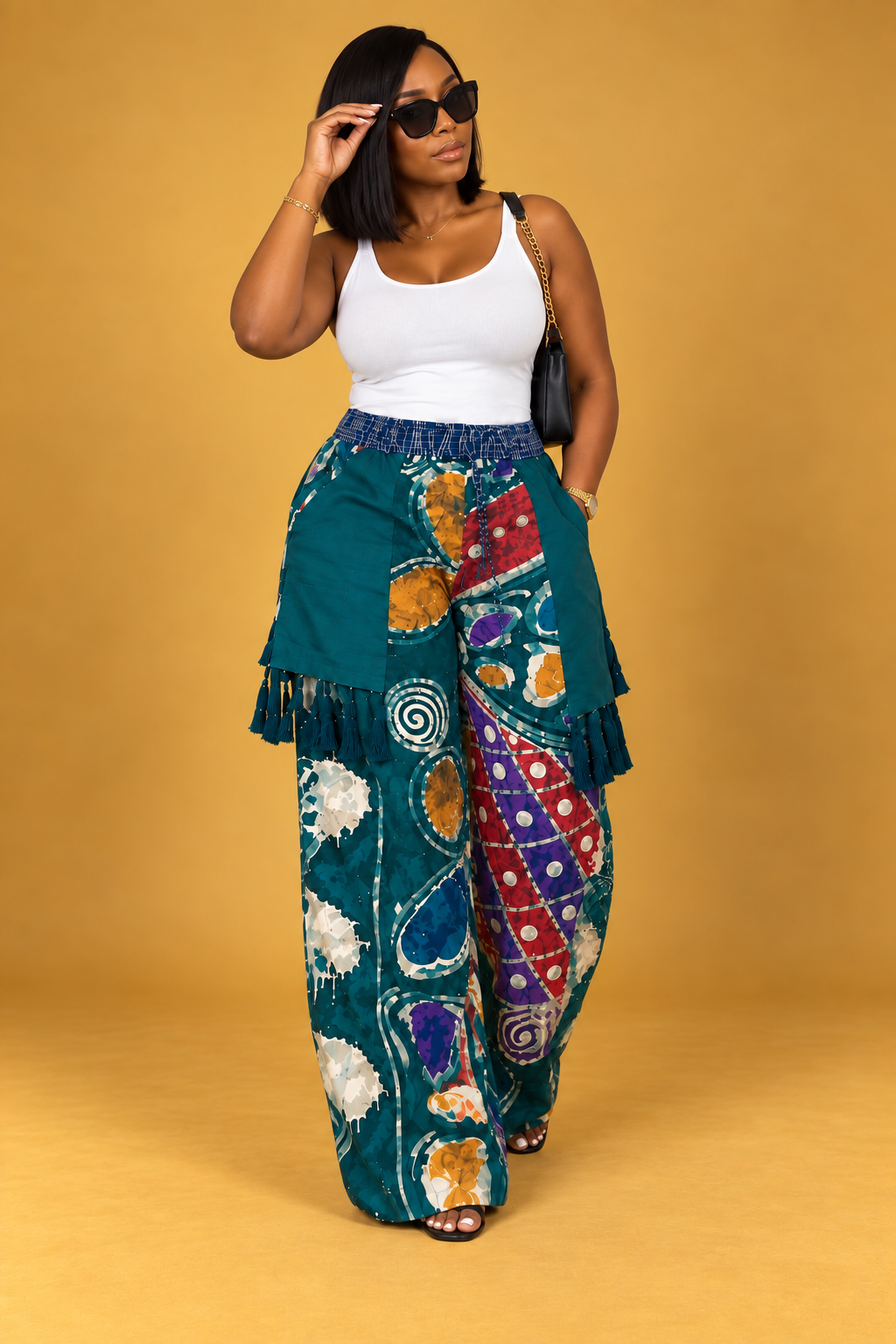 Model wearing teal Adire wide-leg pants with multicolor print, layered panels and tassel details by ILÉ AYỌ̀KÁ.